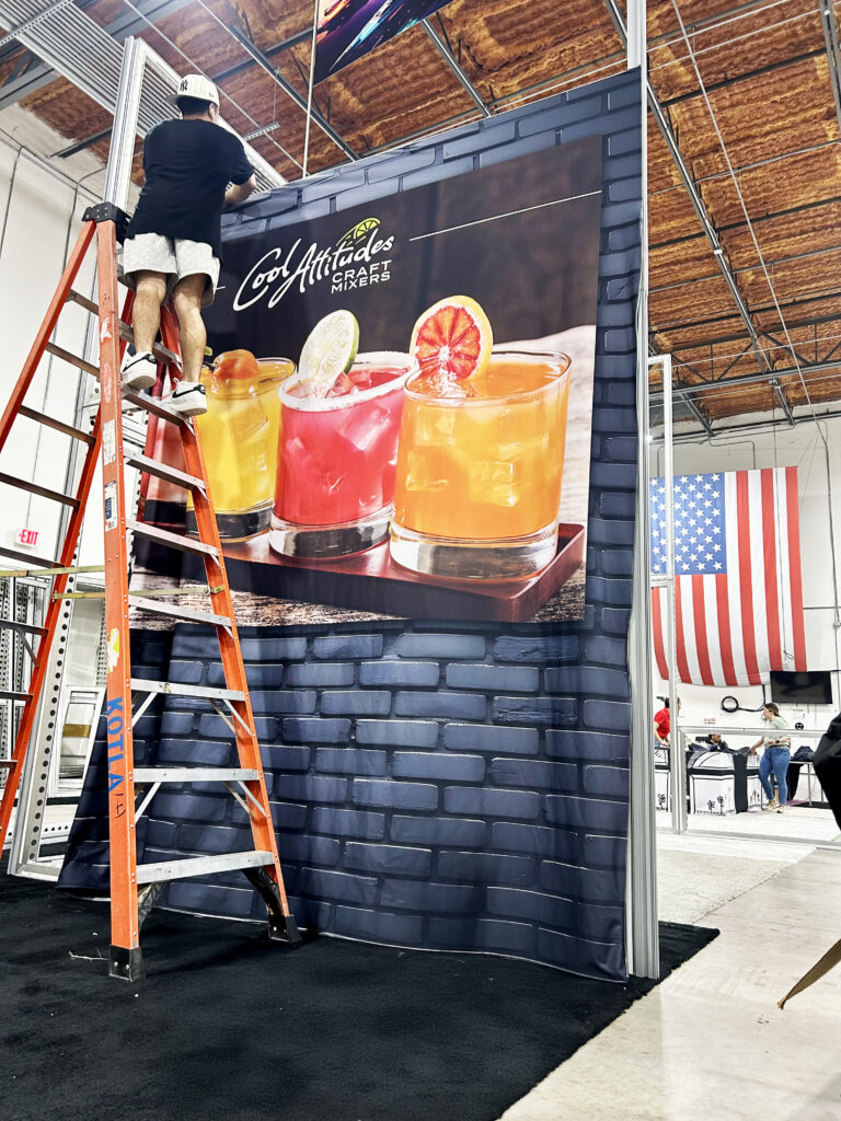 Technician installing SEG graphics on BeMatrix frame during in-house trade show booth fitment in Orlando